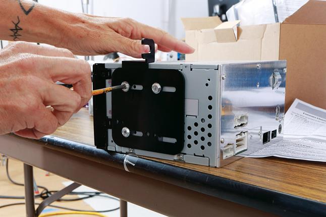 Alex secures the dash kit's brackets to the chassis of the Clarion receiver.